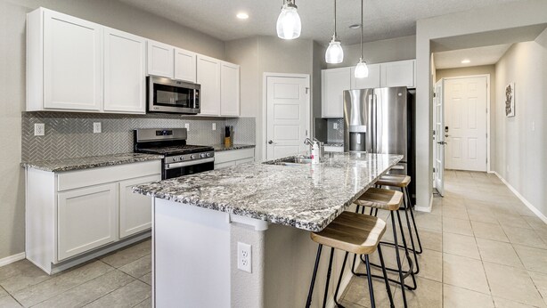 A modern kitchen with white cabinets, granite countertops, stainless steel appliances, and pendant lighting. - Suburban Santa Fe Home Near Main Street & I-25 (Los Lunas)