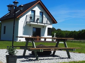 Ein weißes Gebäude mit Balkon, einer Holzbank und einem Blumentopf.
