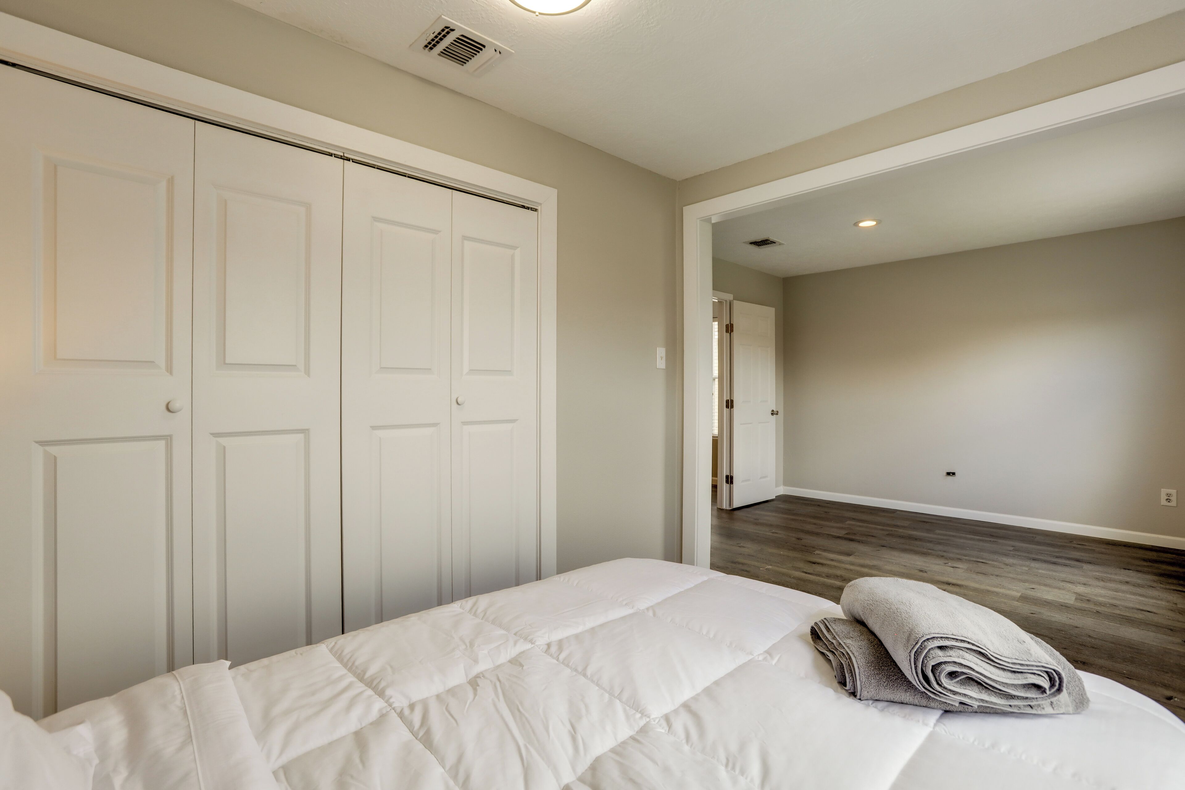 A bedroom with a bed, a closet, and a hallway leading to another room.