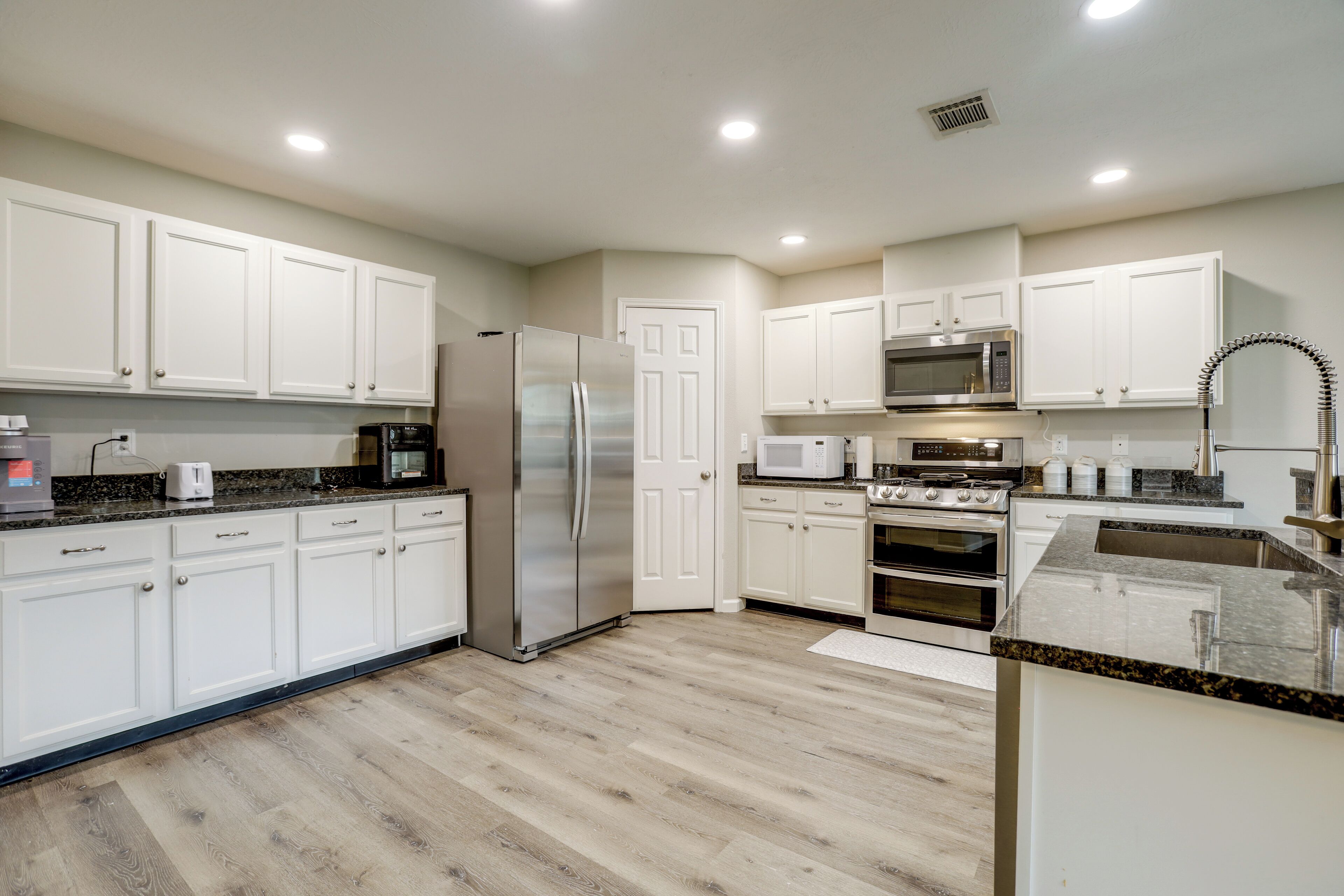 A modern kitchen with white cabinets, stainless steel appliances, and a granite countertop.