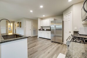 A modern kitchen with white cabinets, a stainless steel refrigerator, and a granite countertop. - Near The Woodlands! Group Retreat w/ Yard & Patio (Spring)