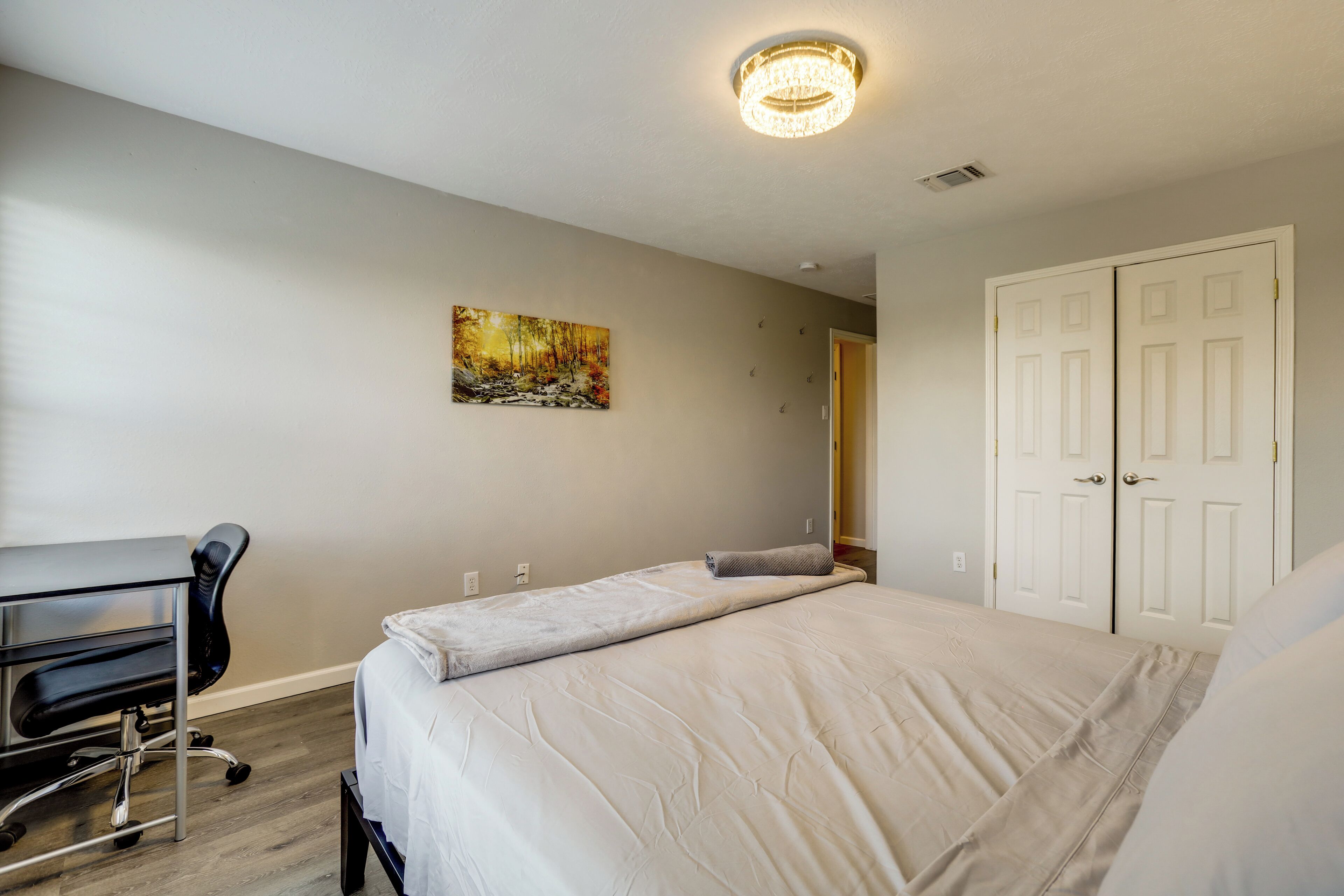 Une chambre à coucher avec un lit, un bureau, une chaise, un tableau et une armoire.