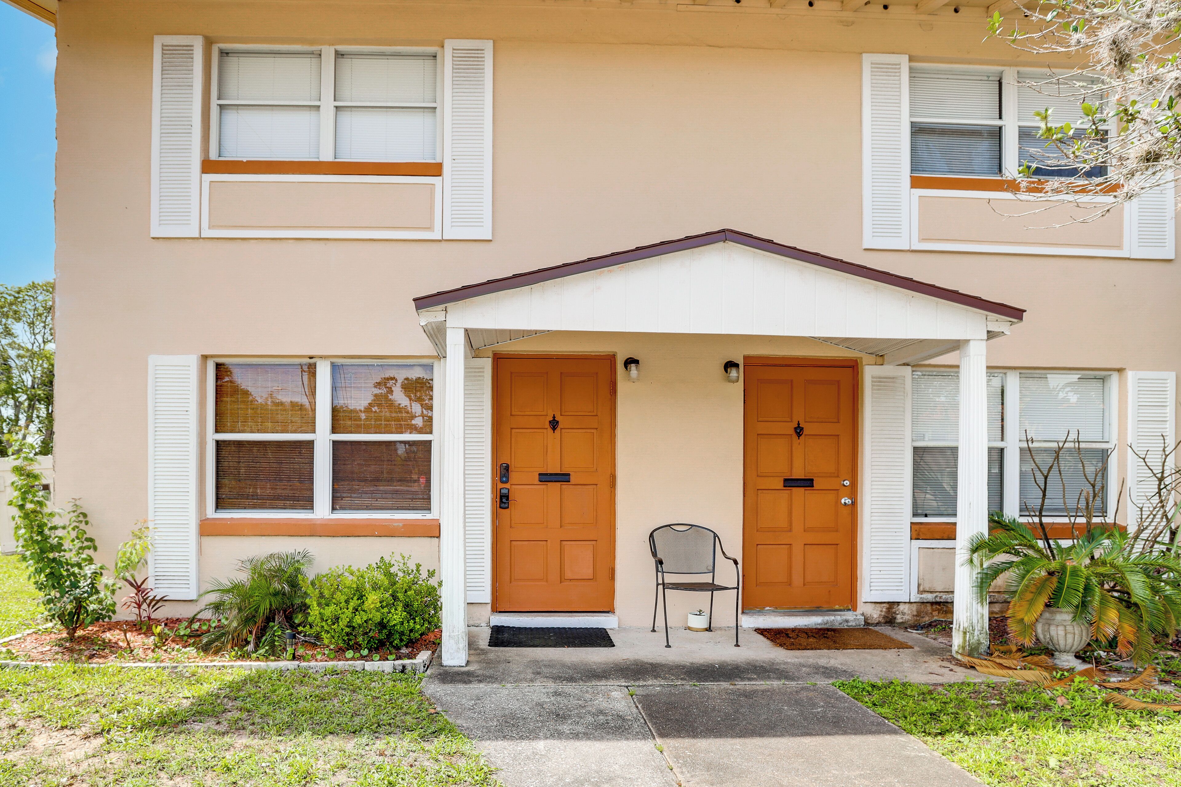 A two-story building with a front porch, two doors, and a small chair.