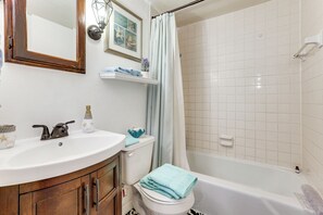 Et badeværelse med hvid vask, toilet og badekar.