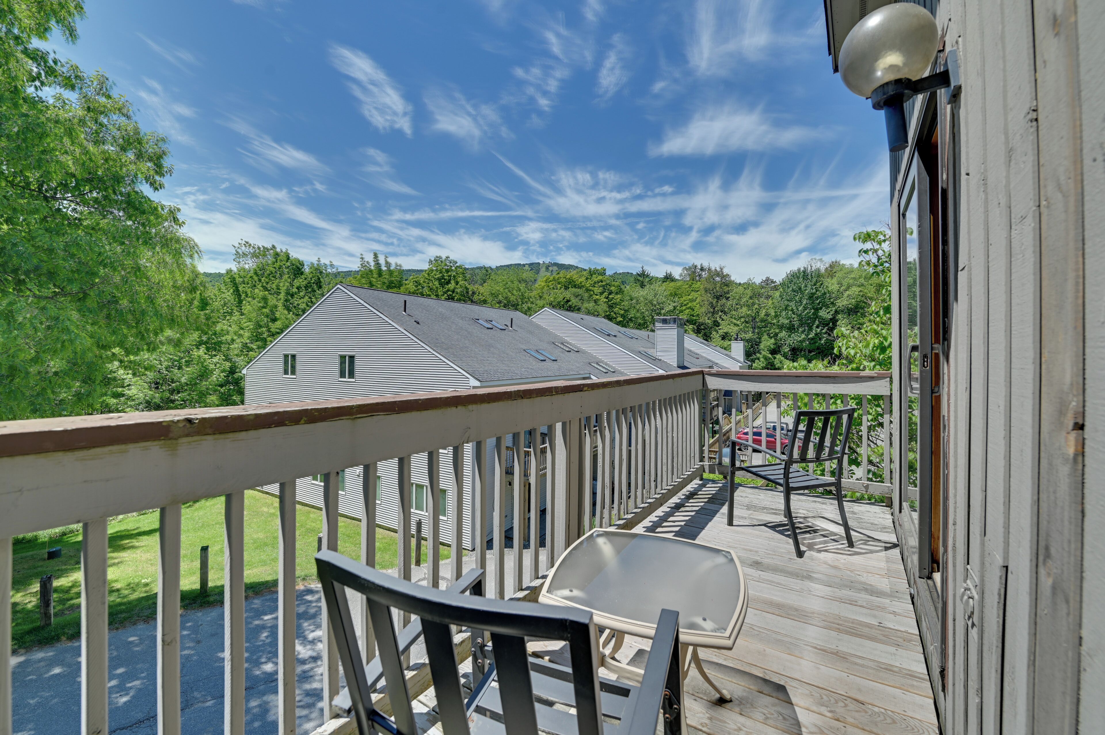 A wooden deck with a railing, a table, and a chair.