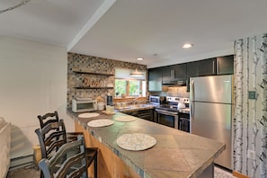 A modern kitchen with a central island, built-in appliances, and a window providing natural light. - Hike, Bike & Ski! Condo Steps to Mount Snow Resort (West Dover)