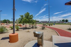 A desert landscape with a red pathway, a metal pole, and a small structure.