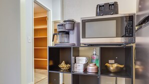 A kitchenette with a coffee maker, microwave, and shelves with decorative items. - Convenient High Desert Stay Near Route 66 (Victorville)
