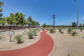 A paved pathway, desert vegetation, and a clear sky.