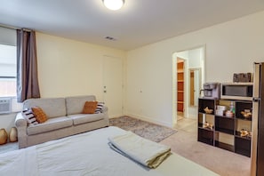 A bedroom with a bed, a sofa, a coffee machine, a TV, and a bookshelf. - Convenient High Desert Stay Near Route 66 (Victorville)