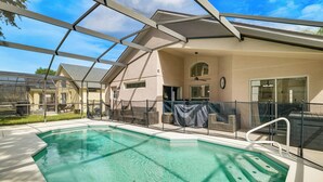 Una piscina techada con techo de vidrio, un área de patio con asientos y vistas a edificios cercanos.