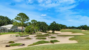 Un campo de golf con búnkeres de arena, una casa club y árboles circundantes.