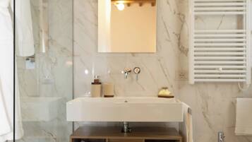 Un bagno moderno con una parete in marmo, un mobile bagno in legno, un bidet e una cabina doccia in vetro.