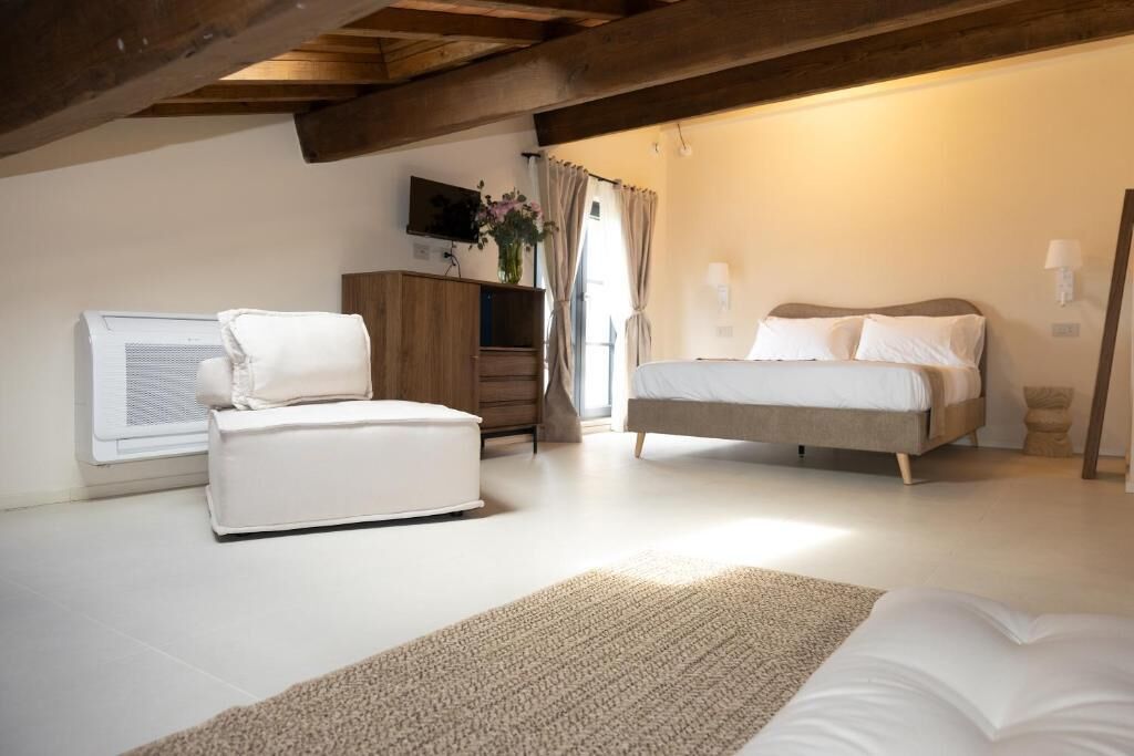 Ein Schlafzimmer mit Bett, einer Couch, einem Fernseher und einem Fenster mit Vorhängen.
