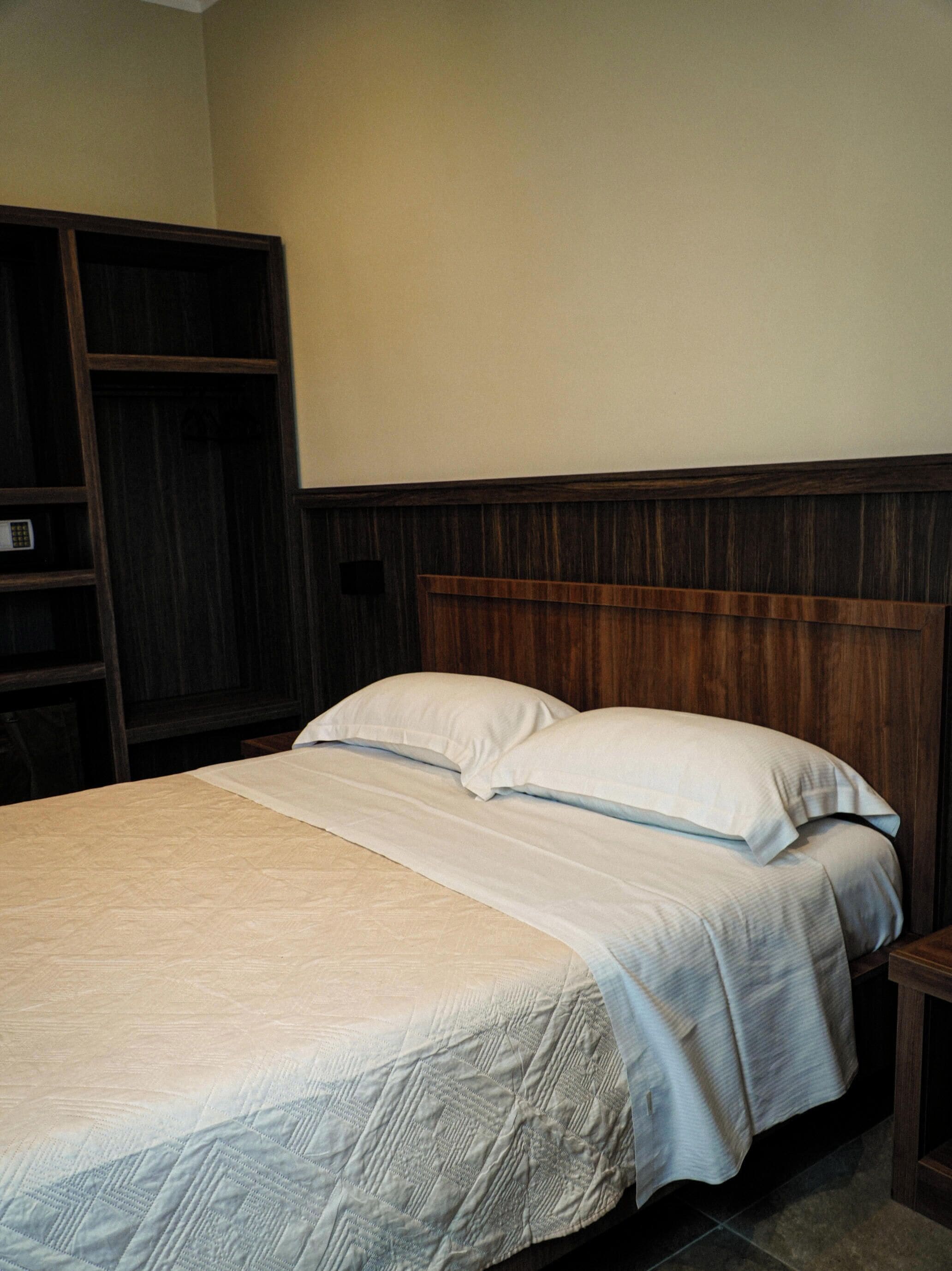 A bed with a wooden headboard, a bedside table, and a wardrobe.