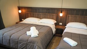 Ein Hotelzimmer mit zwei Betten, jedes mit einem hölzernen Kopfteil und einem kleinen Nachttisch.