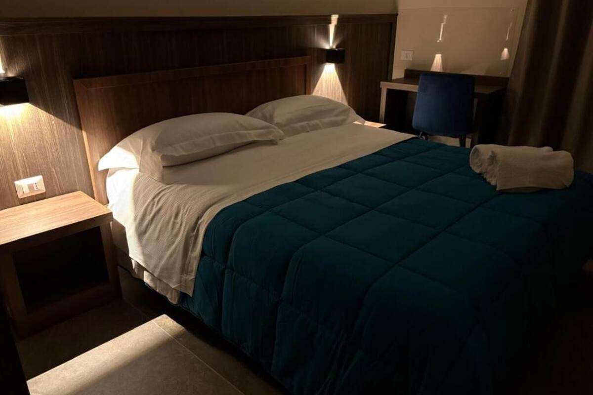 A hotel room with a bed, bedside tables, a desk, and a chair.