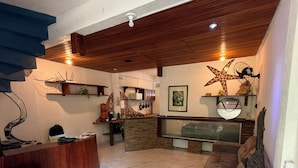 Amplia sala de estar con techo de madera, un mostrador de recepción, un sofá y una mesa de centro.
