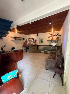 A spacious living area with a wooden ceiling, a reception desk, a sofa, and a coffee table.