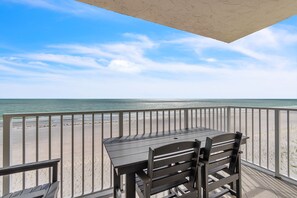 A balcony with a table and chairs overlooking a beach. - ☀Beachfront🌴Heated Pool🐠Direct Beach Access🐬Gulf Shores 402 (Indian Shores)