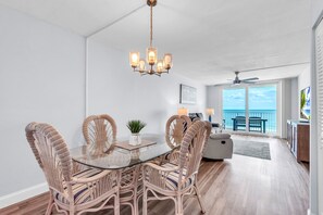 A dining area with wicker chairs, a glass table, and a chandelier. - ☀Beachfront🌴Heated Pool🐠Direct Beach Access🐬Gulf Shores 402 (Indian Shores)