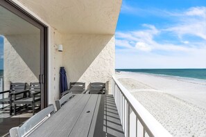 A balcony with a table and chairs, overlooking a beach. - ☀Beachfront🌴Heated Pool🐠Direct Beach Access🐬Gulf Shores 402 (Indian Shores)