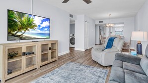 Ein Wohnzimmer mit Fernseher, Holzschrank, grauem Sofa und Deckenventilator.