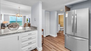 Eine moderne Küche mit einem Edelstahl-Kühlschrank, weißen Schränken und Holzboden.