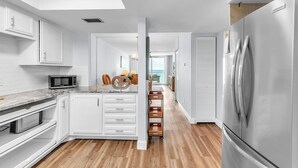 Eine moderne Küche mit weißen Schränken, einem Edelstahl-Kühlschrank und Holzboden.