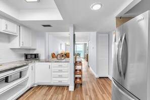Eine moderne Küche mit weißen Schränken, einem Edelstahl-Kühlschrank und Holzboden.