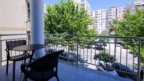 A balcony with two chairs and a table, overlooking a street with parked cars and buildings. - Toro Double Room With City View (Durrës)