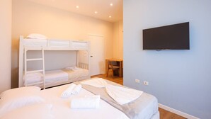 Une chambre avec des lits superposés, un bureau et un téléviseur.