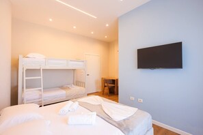 Ein Schlafzimmer mit Etagenbetten, einem Schreibtisch und einem Fernseher.