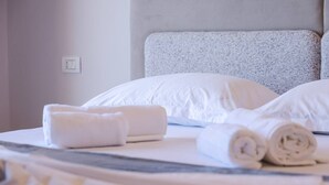 Un lit bien fait, avec du linge de lit blanc et des serviettes enroulées.