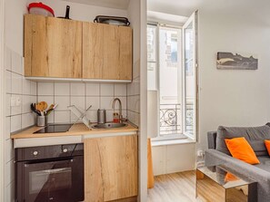Eine kompakte Küche mit Holzausstattung, einem eingebauten Backofen und einem Spülbecken.