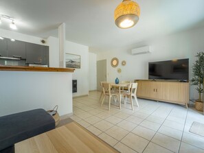 Een moderne woonkamer met een eethoek, een keuken met inbouwoven, een flatscreen-tv en een hanglamp.