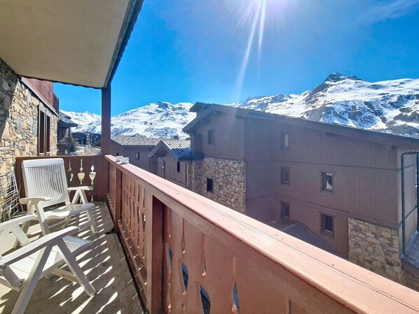 Un balcón con vista a montañas nevadas y edificios tradicionales.
