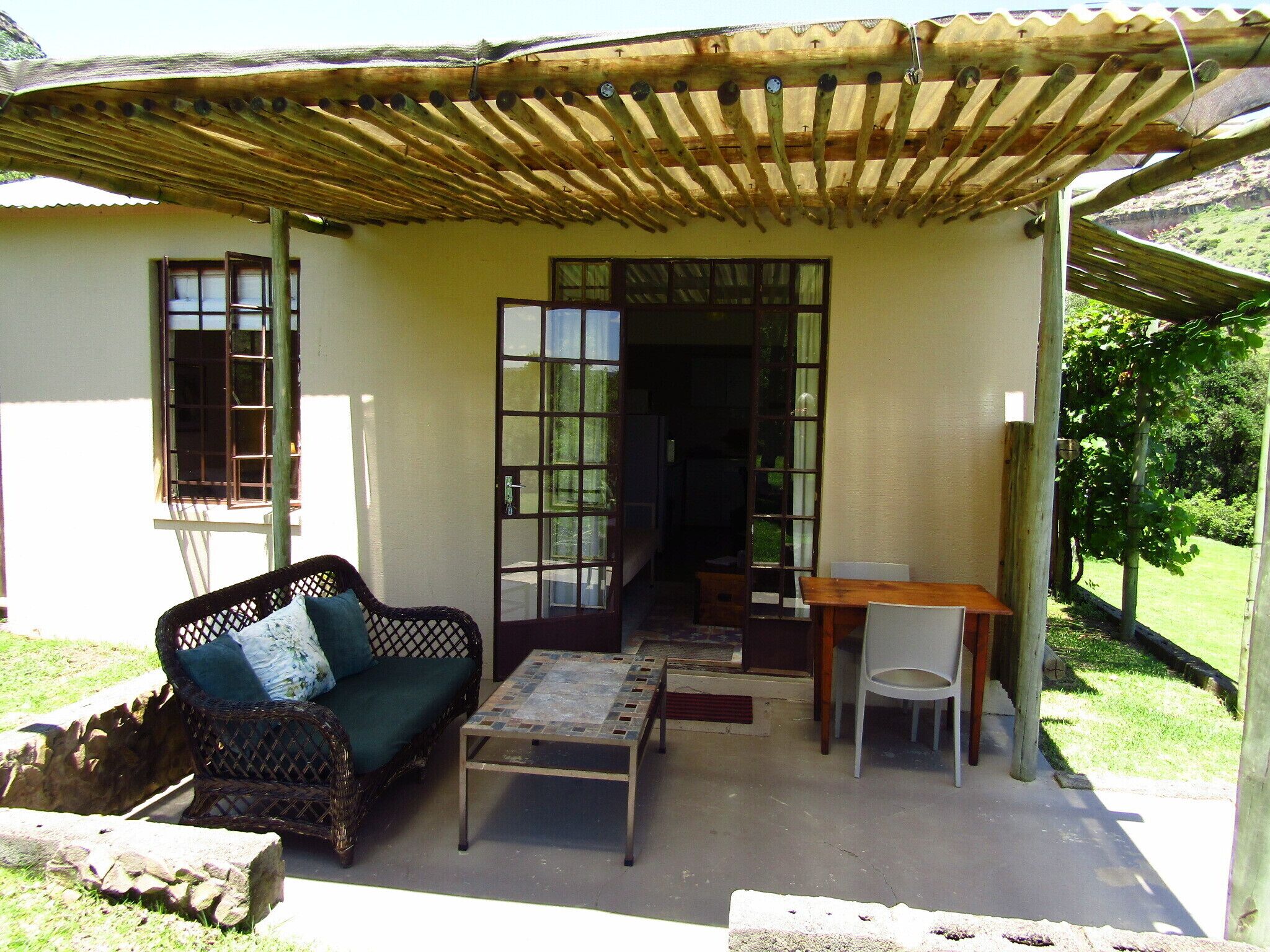 A covered outdoor seating area with a sofa, table, and chairs.