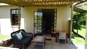A covered outdoor seating area with a sofa, table, and chairs. - Mafube Mountain Retreat (Fouriesburg)