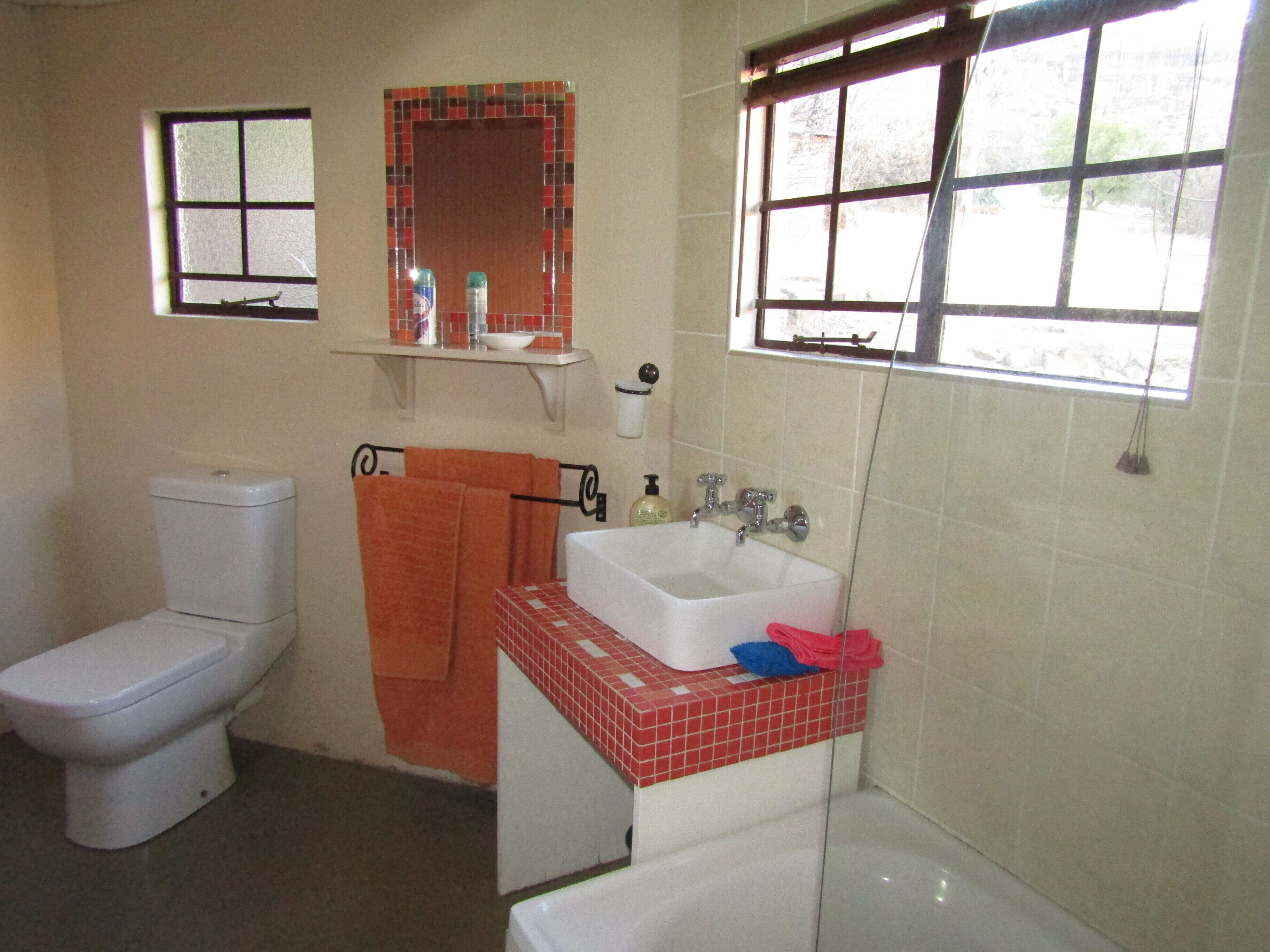 A bathroom with a toilet, sink, and bathtub. There are two windows providing natural light.