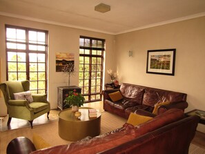 A living room with a green armchair, brown leather sofa, and a round coffee table. - Mafube Mountain Retreat (Fouriesburg)