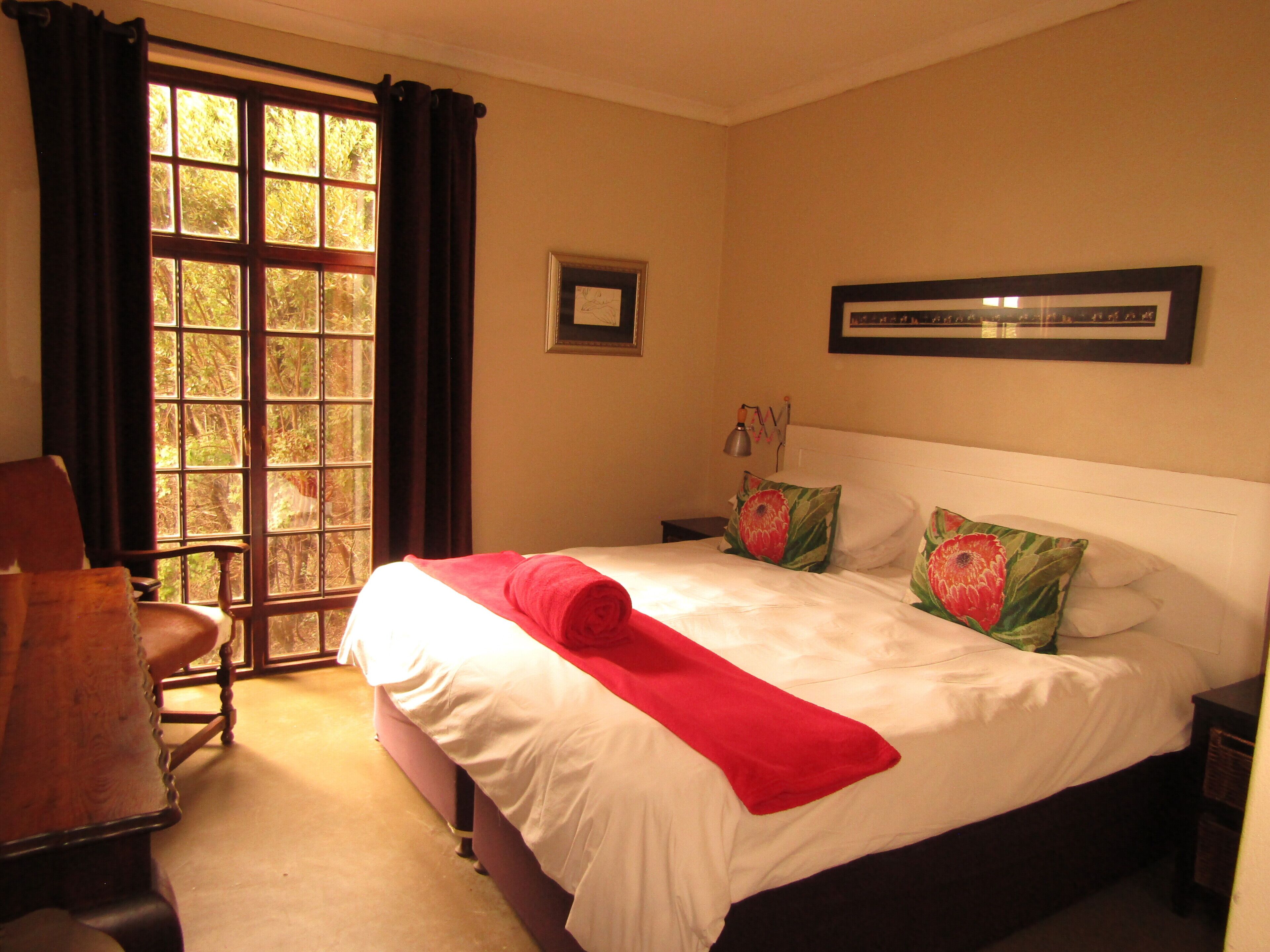 A hotel room with a large bed, a chair, a nightstand, and a window with curtains.