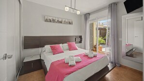 Un dormitorio moderno con una cama grande, cabecera, mesita de noche y vistas al exterior a través de una puerta corrediza de vidrio.