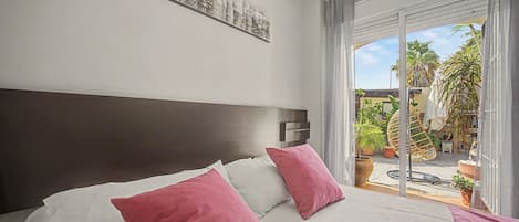 Een hotelkamer met een bed, een hoofdeinde, een nachtkastje, een raam met uitzicht op de omgeving en een aan de muur bevestigd kunstwerk.