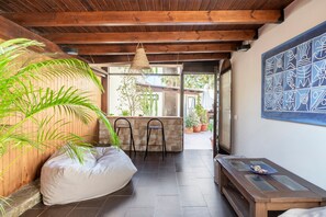 A room with a wooden ceiling, a large plant, a bean bag, a table with a glass top, and a wall with a geometric mural. - Apartamento 'Con Terraza' con Piscina Compartida, Wi-Fi y Aire Acondicionado (Tarifa)