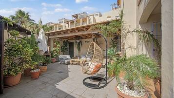 Ein Patio im Freien mit einer Hängematte, Blumentöpfen und einer Couch.