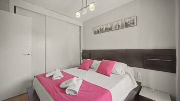 A hotel room with a bed, a headboard, a wall-mounted artwork, and a bedside table.