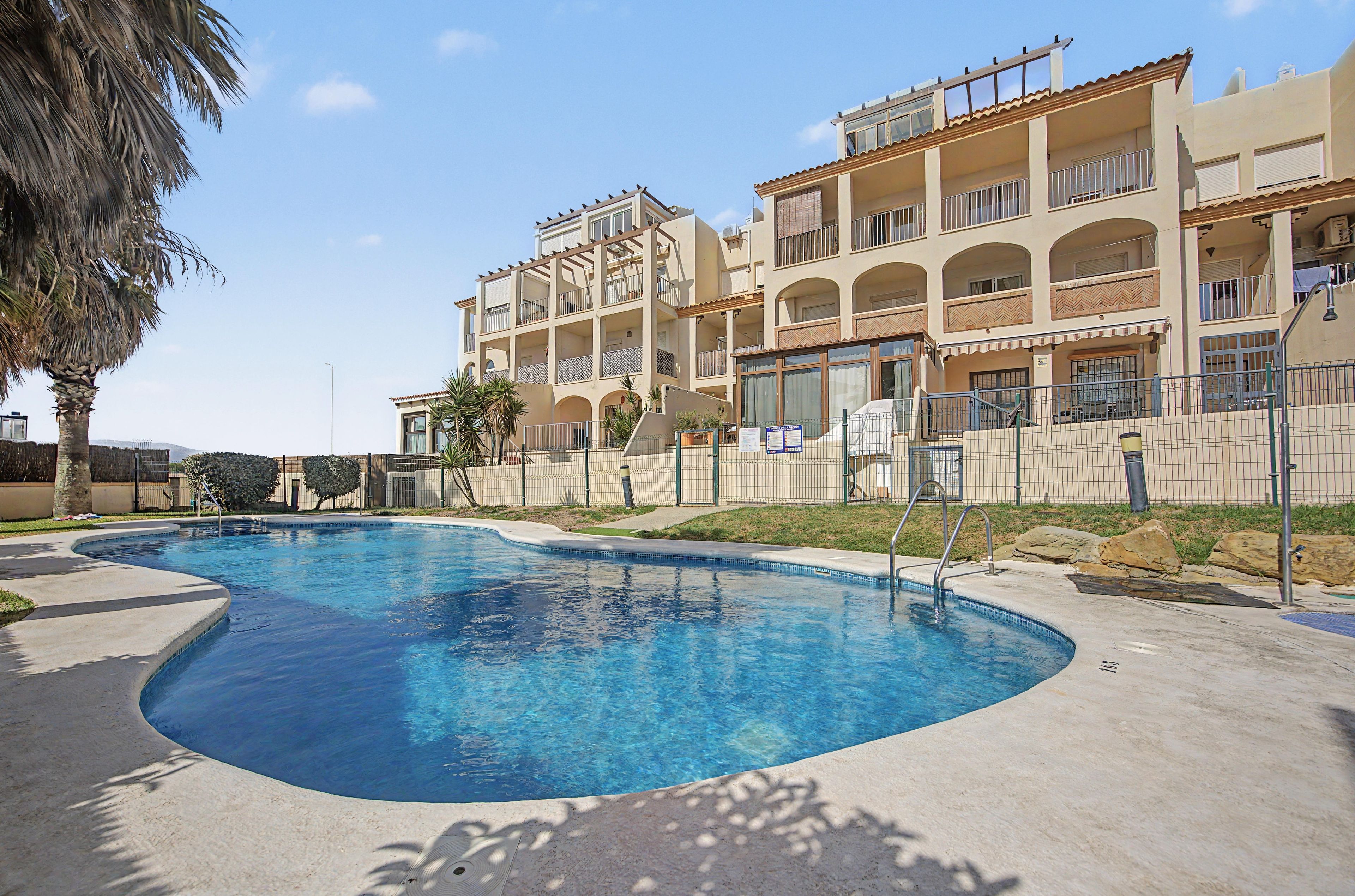 A swimming pool with a curved edge, surrounded by a concrete deck.