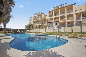 A swimming pool with a curved edge, surrounded by a concrete deck. - Apartamento 'Con Terraza' con Piscina Compartida, Wi-Fi y Aire Acondicionado (Tarifa)