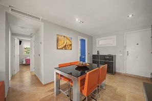 A modern dining area with a black table, orange chairs, and a blue door in the background. - Apartamento 'Con Terraza' con Piscina Compartida, Wi-Fi y Aire Acondicionado (Tarifa)